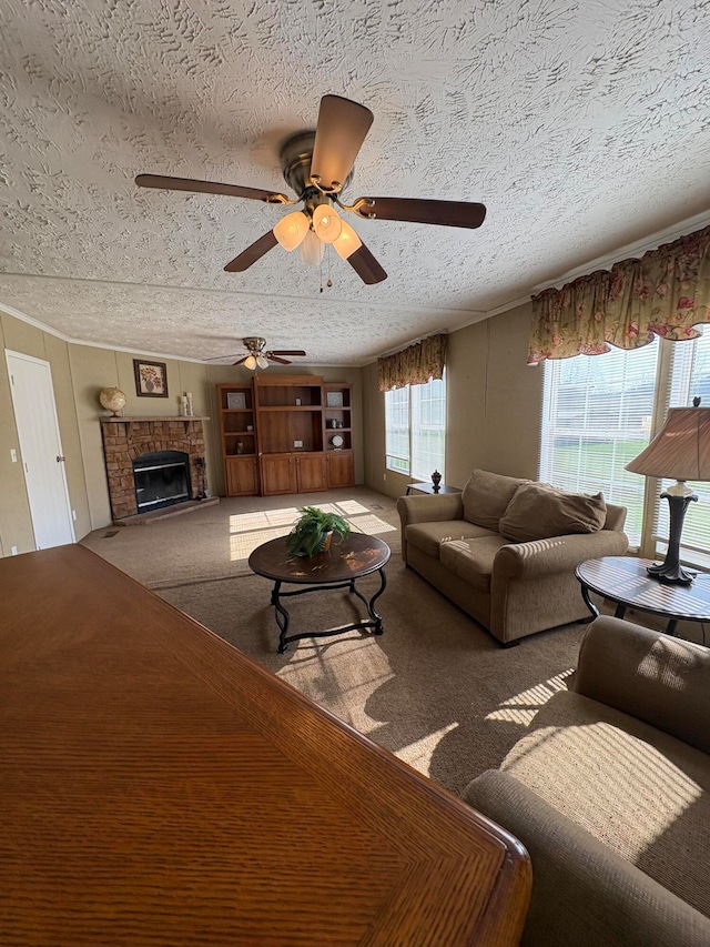 living room featuring carpet flooring, a textured ceiling, ceiling fan, and a stone fireplace