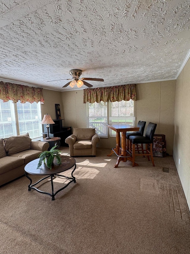 living room featuring carpet, a textured ceiling, ceiling fan, and crown molding