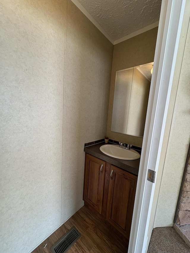580 Bales Creek Rd, Manchester, KY 40962 - bathroom with vanity, a textured ceiling, wood finished floors, a textured wall, and crown molding