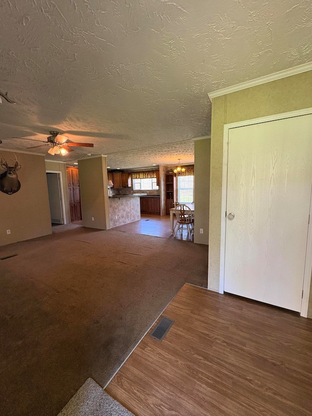 interior space featuring ornamental molding, a textured ceiling, dark carpet, and ceiling fan