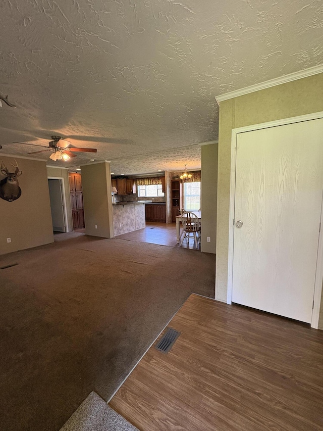 580 Bales Creek Rd, Manchester, KY 40962 - unfurnished living room with a chandelier, a textured ceiling, ceiling fan, ornamental molding, and wood finished floors