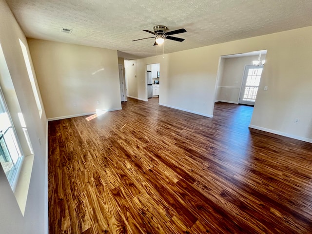 unfurnished room featuring a textured ceiling, dark hardwood / wood-style floors, and ceiling fan with notable chandelier