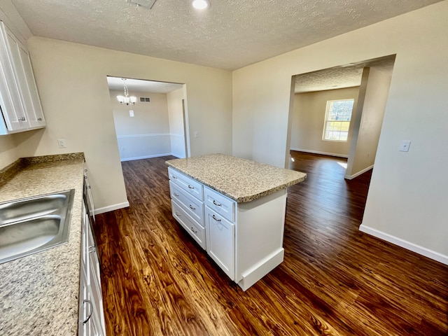 kitchen with white cabinets, a textured ceiling, and dark hardwood / wood-style floors