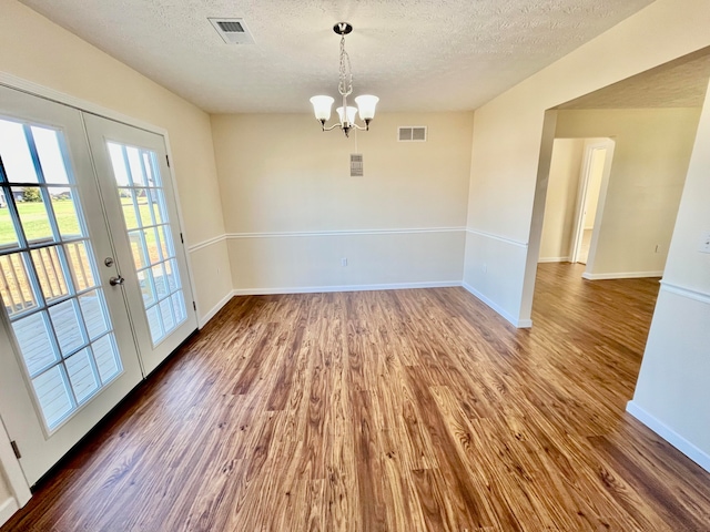 unfurnished dining area with dark wood-type flooring, french doors, and a textured ceiling