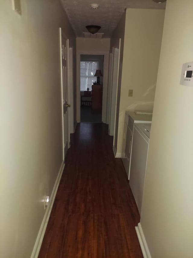 hallway with separate washer and dryer and dark hardwood / wood-style flooring