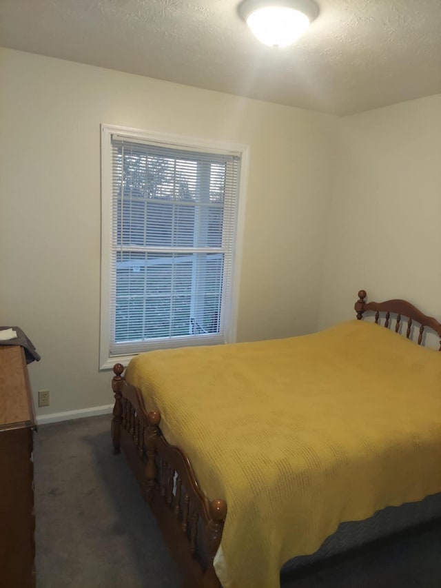 bedroom featuring a textured ceiling and dark carpet