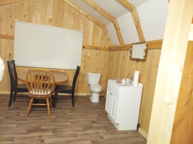 dining room featuring hardwood / wood-style flooring, wooden walls, and lofted ceiling