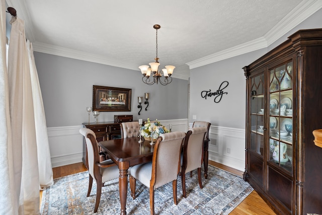 dining area featuring wood-type flooring, a notable chandelier, and ornamental molding