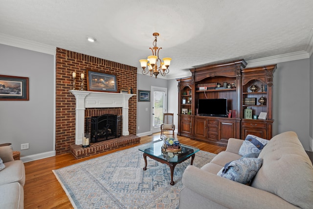 living room featuring ornamental molding, a fireplace, a textured ceiling, an inviting chandelier, and hardwood / wood-style flooring