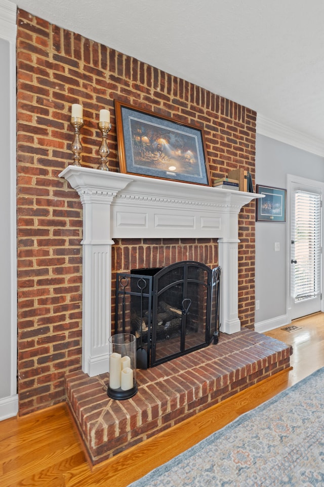 room details featuring a fireplace, wood-type flooring, and ornamental molding