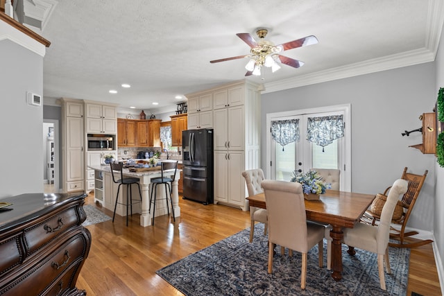 dining room with light wood-type flooring, a textured ceiling, crown molding, and ceiling fan