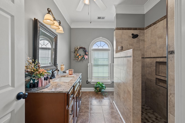 bathroom with tiled shower, ornamental molding, vanity, and ceiling fan