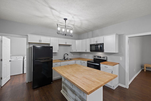 kitchen featuring pendant lighting, washing machine and dryer, white cabinets, and black appliances