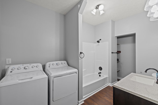 clothes washing area featuring washing machine and clothes dryer, dark hardwood / wood-style floors, a textured ceiling, and sink