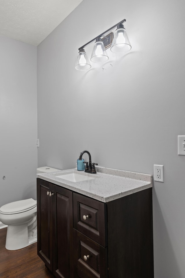 bathroom featuring toilet, vanity, wood-type flooring, and a textured ceiling