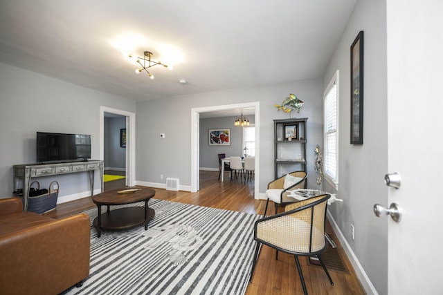 living room featuring wood-type flooring and an inviting chandelier