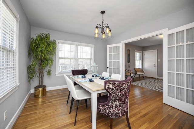 dining area featuring hardwood / wood-style flooring, french doors, and an inviting chandelier