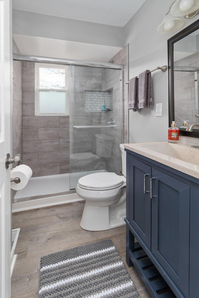 bathroom featuring an enclosed shower, vanity, toilet, and hardwood / wood-style flooring