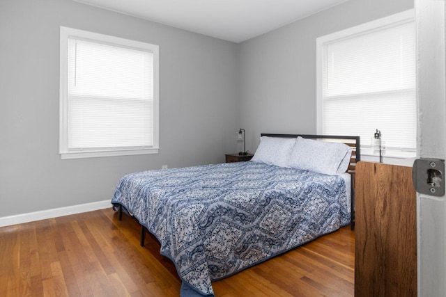 bedroom with multiple windows and hardwood / wood-style flooring