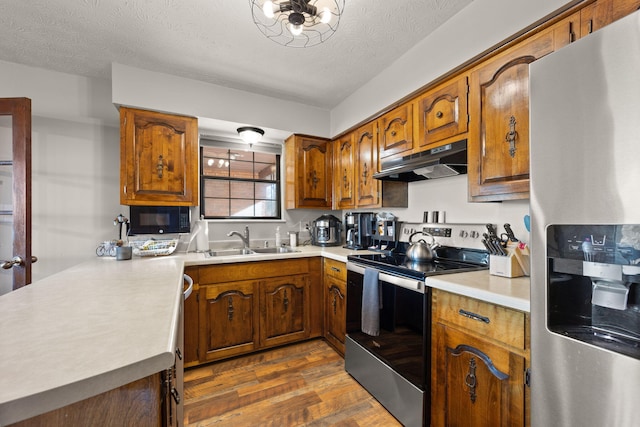 kitchen with kitchen peninsula, dark hardwood / wood-style flooring, a textured ceiling, stainless steel appliances, and sink