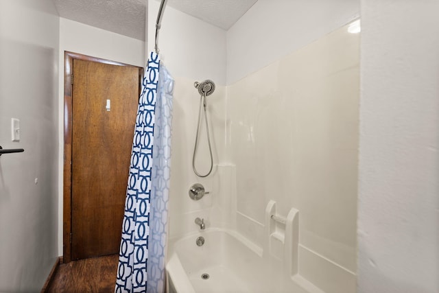 bathroom with hardwood / wood-style floors, shower / bath combo, and a textured ceiling