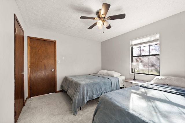 bedroom featuring ceiling fan, light colored carpet, a textured ceiling, and a closet