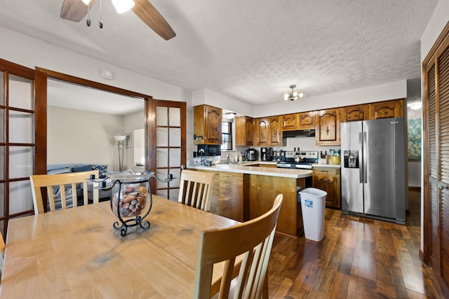 kitchen with a textured ceiling, kitchen peninsula, dark hardwood / wood-style floors, and appliances with stainless steel finishes