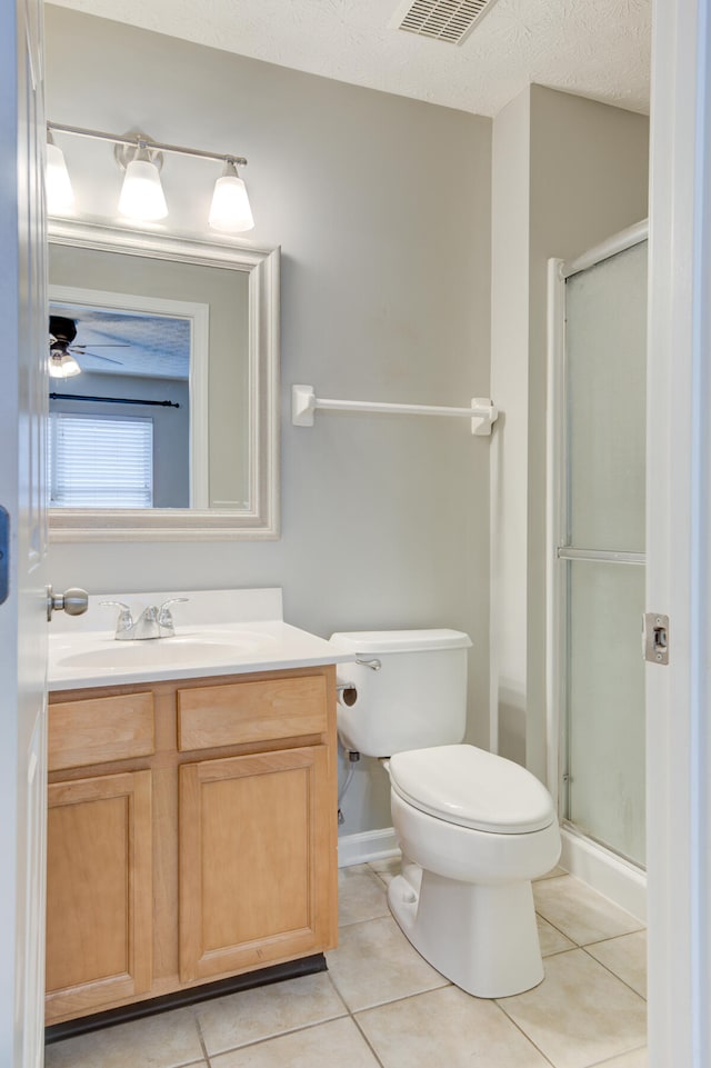 bathroom featuring vanity, tile patterned floors, toilet, a textured ceiling, and walk in shower