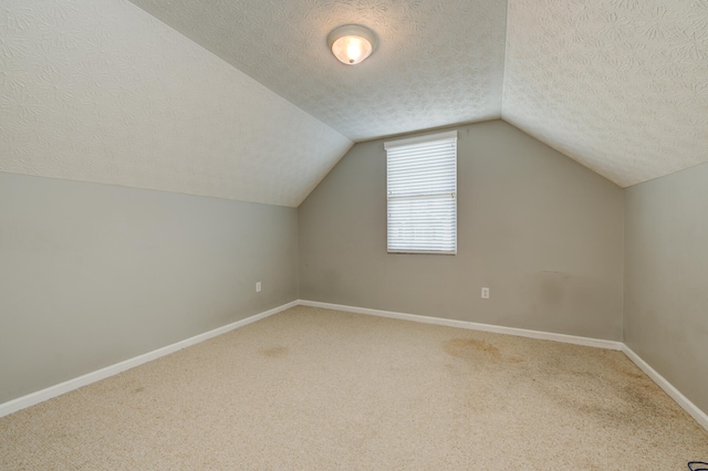 additional living space with carpet, a textured ceiling, and vaulted ceiling