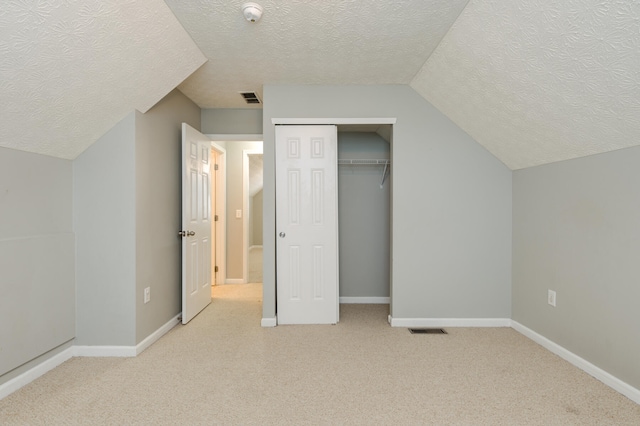 additional living space with light colored carpet, a textured ceiling, and vaulted ceiling