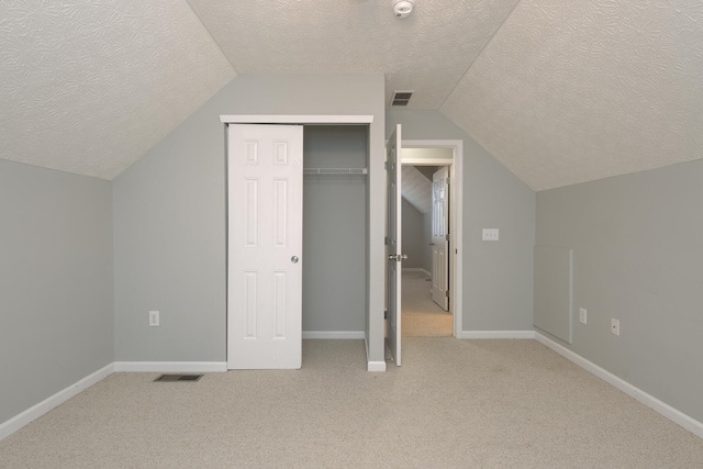 additional living space with a textured ceiling, light carpet, and vaulted ceiling