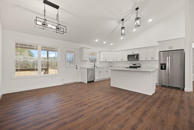 kitchen featuring stainless steel appliances, high vaulted ceiling, white cabinets, dark hardwood / wood-style floors, and hanging light fixtures