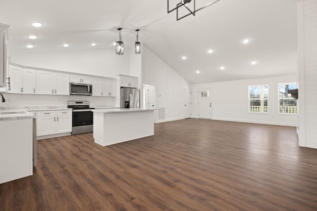 kitchen featuring stainless steel appliances, dark wood-type flooring, pendant lighting, white cabinets, and a kitchen island