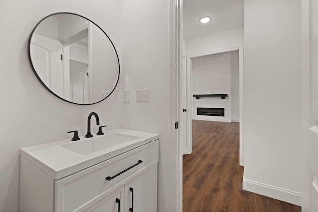 bathroom with wood-type flooring, vanity, and a large fireplace