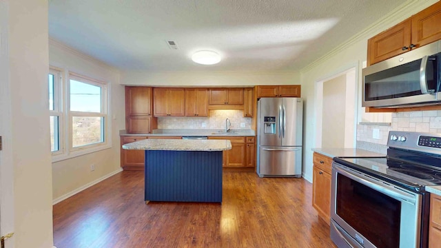 kitchen featuring dark hardwood / wood-style floors, sink, backsplash, a center island, and stainless steel appliances