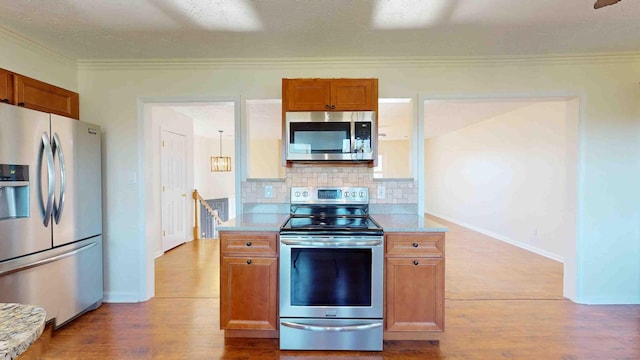 kitchen featuring tasteful backsplash, a textured ceiling, light wood-type flooring, ornamental molding, and appliances with stainless steel finishes