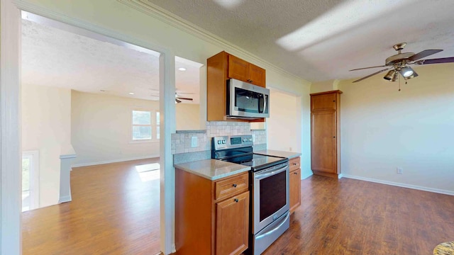 kitchen with appliances with stainless steel finishes, tasteful backsplash, dark hardwood / wood-style flooring, ceiling fan, and a textured ceiling