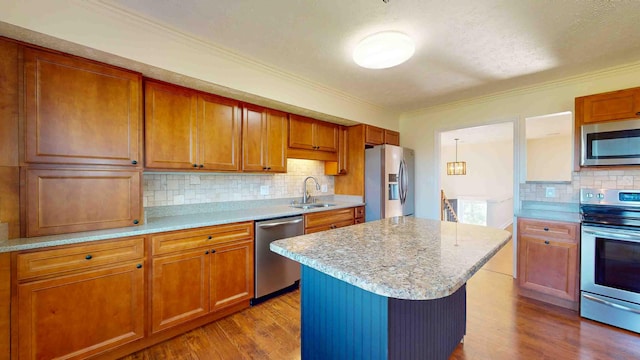 kitchen with stainless steel appliances, a kitchen island, sink, and light hardwood / wood-style floors