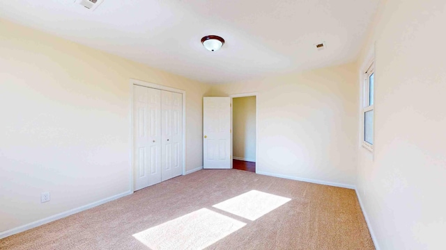 unfurnished bedroom featuring light carpet and a closet