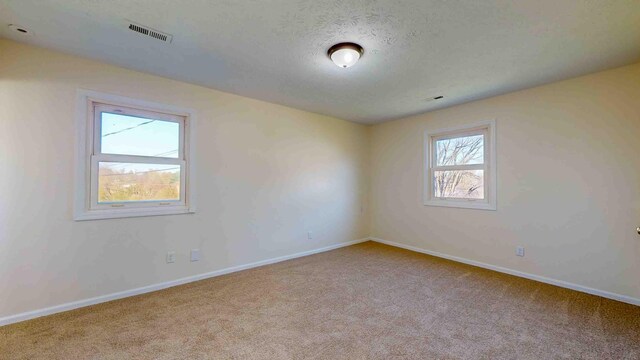 carpeted spare room featuring a textured ceiling