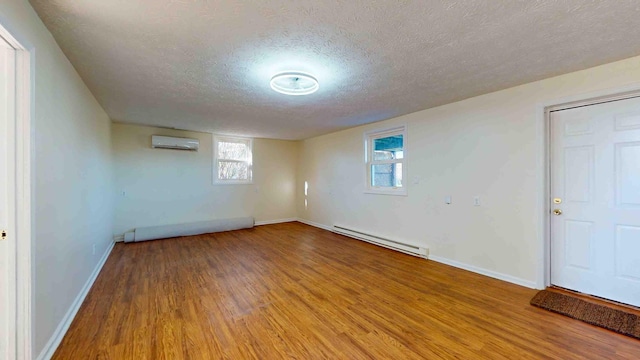 basement featuring baseboard heating, a wall mounted air conditioner, hardwood / wood-style floors, and a textured ceiling