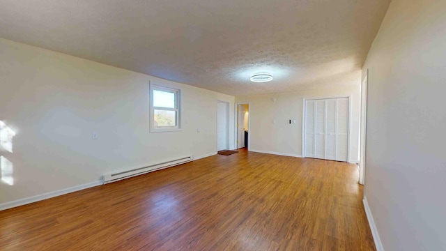 unfurnished room with hardwood / wood-style flooring, a baseboard radiator, and a textured ceiling