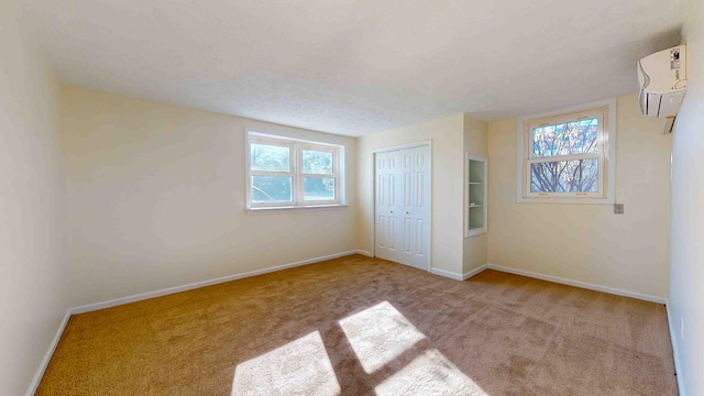 unfurnished bedroom featuring light carpet, a wall mounted AC, and a closet