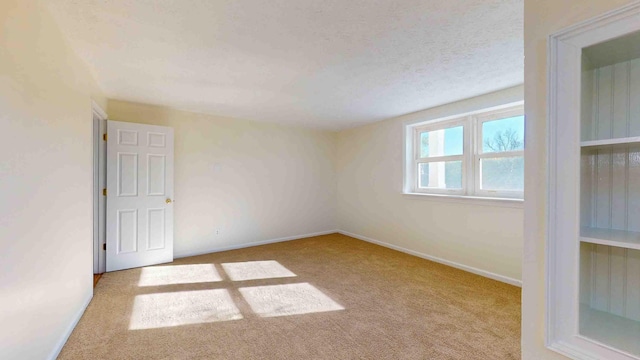 carpeted empty room featuring a textured ceiling