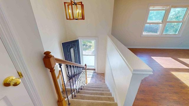 staircase featuring hardwood / wood-style flooring and an inviting chandelier