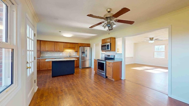 kitchen with tasteful backsplash, stainless steel appliances, wood-type flooring, and a kitchen island