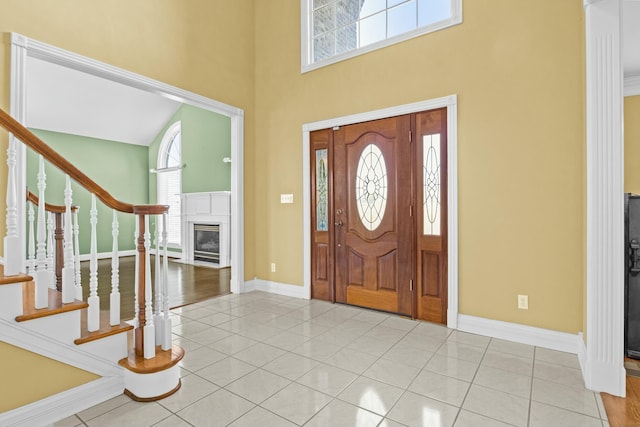 entryway with light tile patterned flooring and a towering ceiling