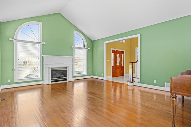 unfurnished living room featuring plenty of natural light, light hardwood / wood-style floors, and vaulted ceiling