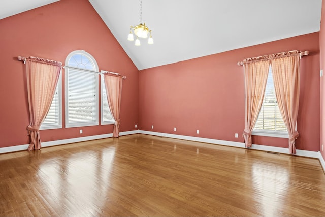 spare room featuring high vaulted ceiling, a chandelier, and hardwood / wood-style floors