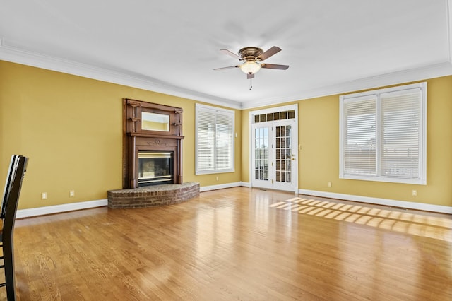 unfurnished living room featuring crown molding, ceiling fan, a fireplace, and light wood-type flooring